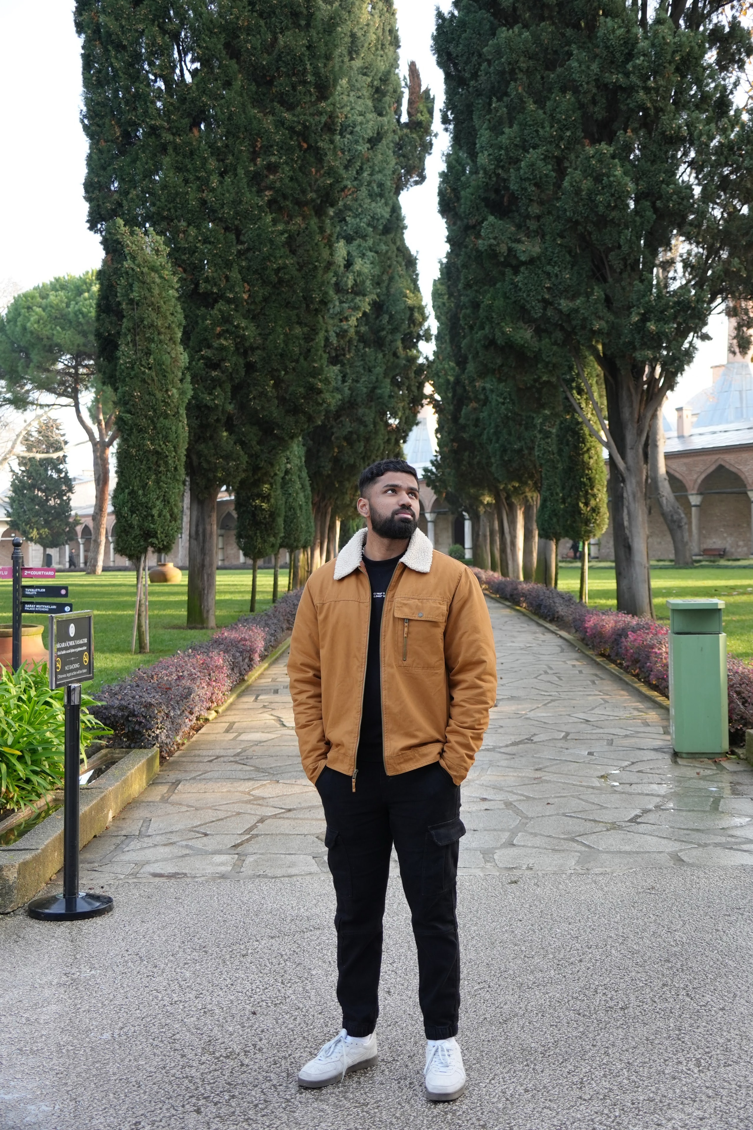 Pranav Saravanan standing on a cypress-lined garden path